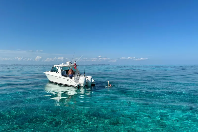 Slide: The Image of 2023 Pursuit DC 326 Dual Console boat cruising on calm water at sunset. - 1