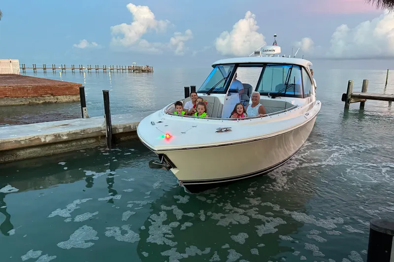 Slide: The Image of 2023 Pursuit DC 326 Dual Console cruising on calm waters at sunset. - 2