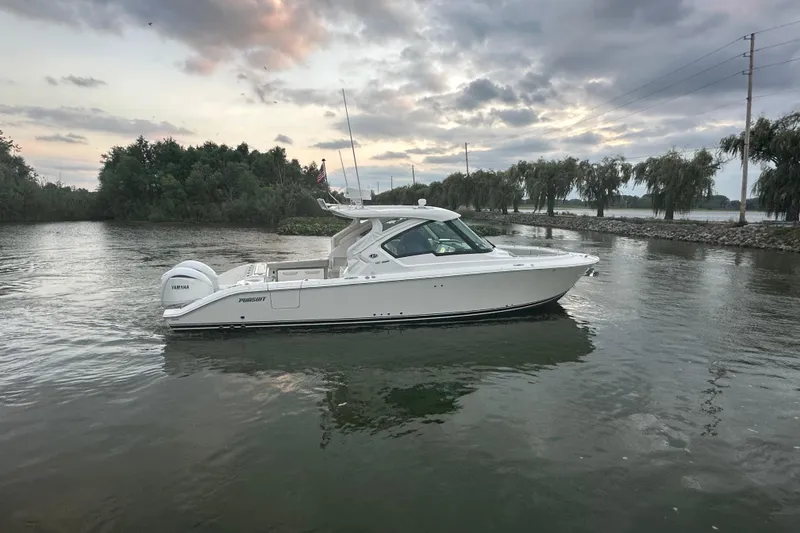 Slide: The Image of 2023 Pursuit DC 326 Dual Console boat deck with open transom door by the water. - 31
