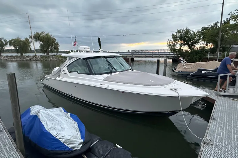 Slide: The Image of 2023 Pursuit DC 326 Dual Console boat docked at marina under cloudy sky. - 43