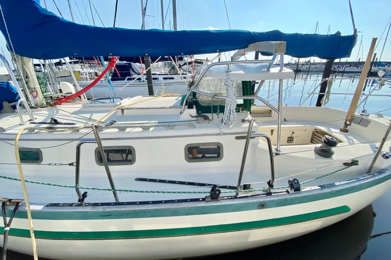 Slide: The Image of 1993 Pacific Seacraft 34 sailboat docked, featuring a blue canopy and green trim. - 3