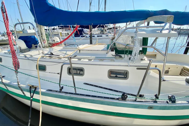 Slide: The Image of 1993 Pacific Seacraft 34 sailboat docked, featuring blue sail cover and white hull. - 4