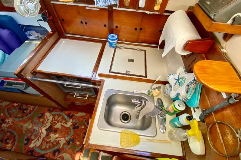 Slide: The Image of 1977 Allied Princess Cutter kitchen with sink, wooden cabinets, and cleaning supplies. - 16