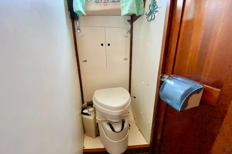 Slide: The Image of 1977 Allied Princess Cutter boat bathroom with compact toilet and wooden accents. - 25