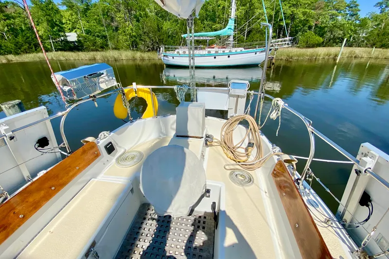 Slide: The Image of Cockpit of 1977 Allied Princess Cutter sailboat, docked on calm water with lush greenery. - 26