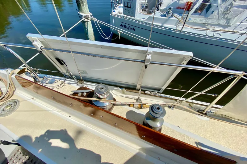Slide: The Image of 1977 Allied Princess Cutter sailboat deck with winches and railing, docked beside another boat. - 27