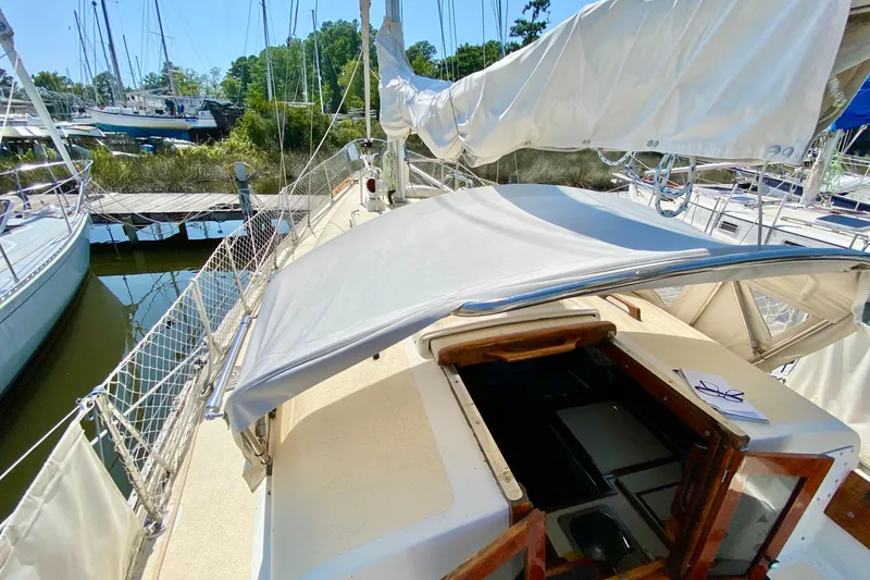 Slide: The Image of 1977 Allied Princess Cutter sailboat docked, featuring a covered cockpit and open cabin entrance. - 28