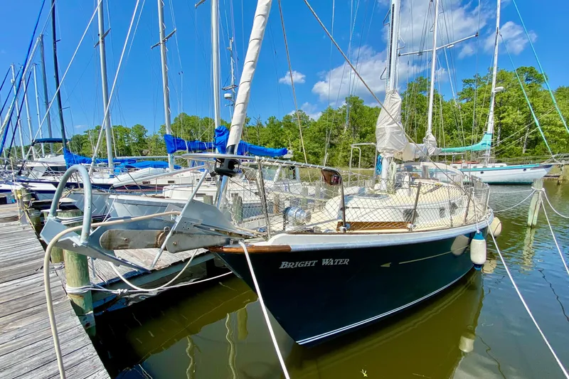 Slide: The Image of 1977 Allied Princess Cutter sailboat docked, named "Bright Water," with clear skies and lush greenery. - 3