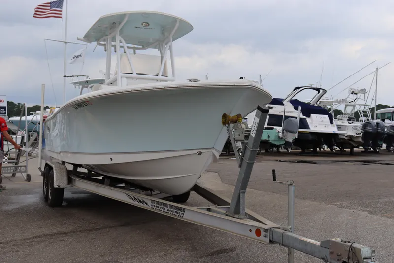 Slide: The Image of 2023 Sea Hunt Ultra 234 boat on trailer at marina, American flag in background. - 23