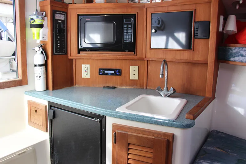 Slide: The Image of 2004 Carolina Classic 28 boat interior with kitchenette, microwave, sink, and fire extinguisher. - 10