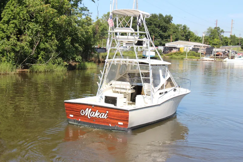 Slide: The Image of 2004 Carolina Classic 28 boat named "Makai" cruising on a calm river. - 25