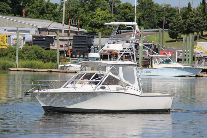 Slide: The Image of 2004 Carolina Classic 28 boat cruising on a calm river near a marina. - 30