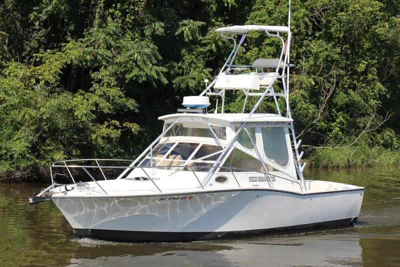 Slide: The Image of 2004 Carolina Classic 28 boat cruising on a river with lush green trees. - 31