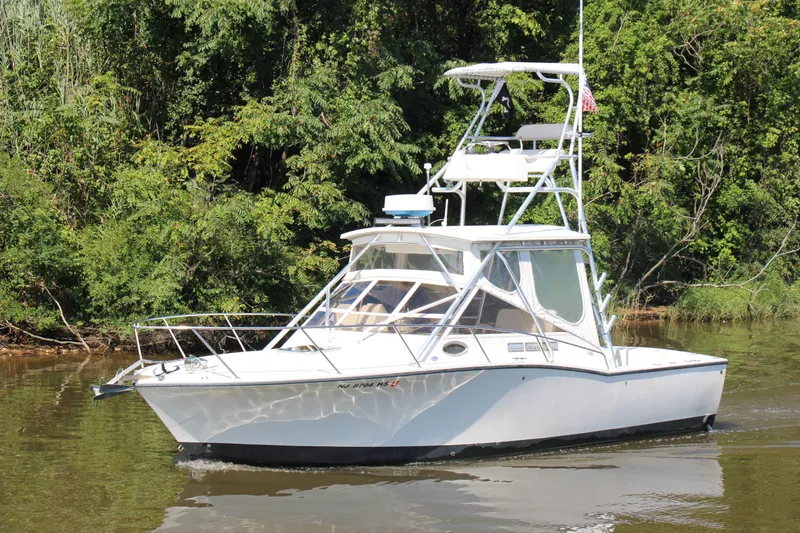 Slide: The Image of 2004 Carolina Classic 28 boat cruising on a river with lush green trees. - 32