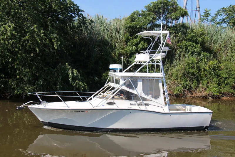 Slide: The Image of 2004 Carolina Classic 28 boat cruising on a calm river, surrounded by lush greenery. - 33