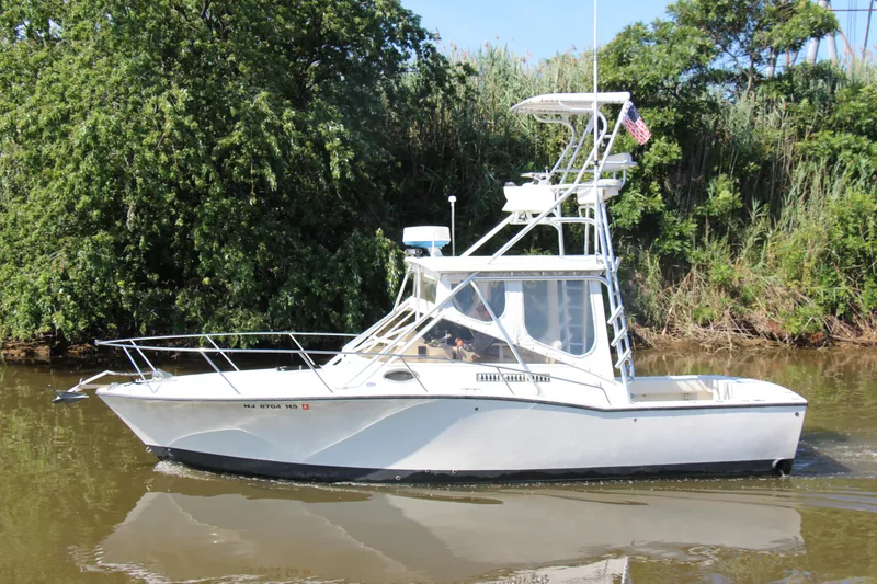 Slide: The Image of 2004 Carolina Classic 28 boat cruising on a river with lush green trees. - 35