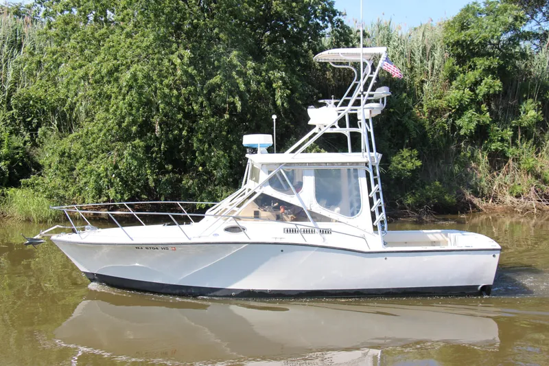 Slide: The Image of 2004 Carolina Classic 28 boat cruising on a calm river with lush greenery. - 36