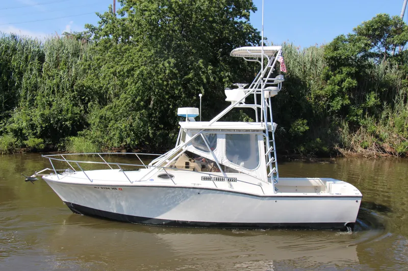 Slide: The Image of 2004 Carolina Classic 28 boat on a calm river, surrounded by lush greenery. - 38