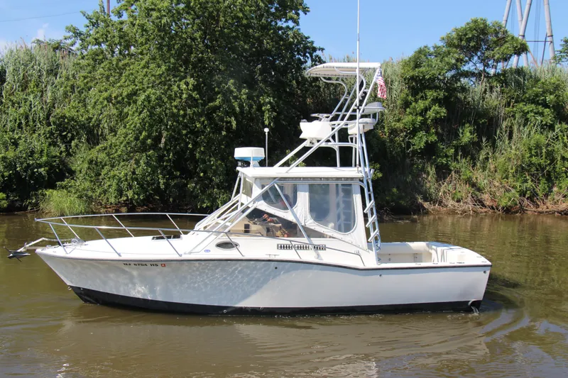 Slide: The Image of 2004 Carolina Classic 28 boat on a calm river, surrounded by lush greenery. - 40