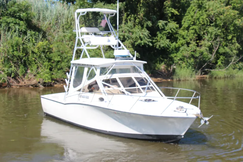Slide: The Image of 2004 Carolina Classic 28 boat cruising on a calm river with lush greenery. - 49