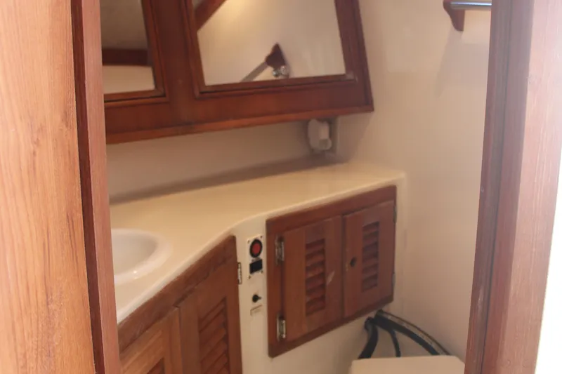 Slide: The Image of 2004 Carolina Classic 28 boat interior with wooden cabinets and mirror in bathroom. - 5