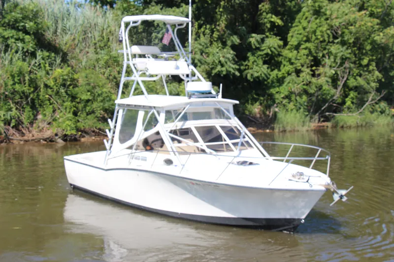 Slide: The Image of 2004 Carolina Classic 28 boat on calm water with lush green background. - 50