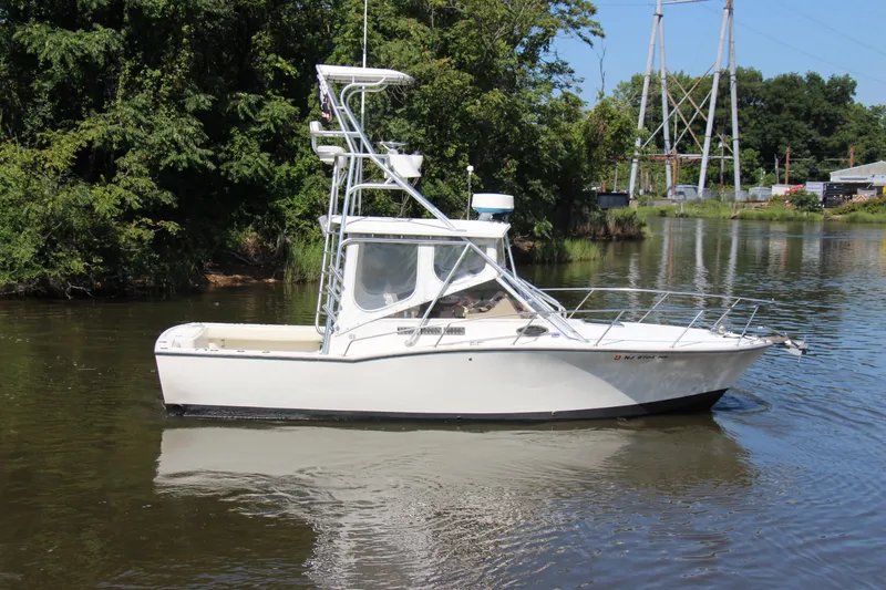 Slide: The Image of 2004 Carolina Classic 28 boat on calm water, surrounded by lush greenery. - 51