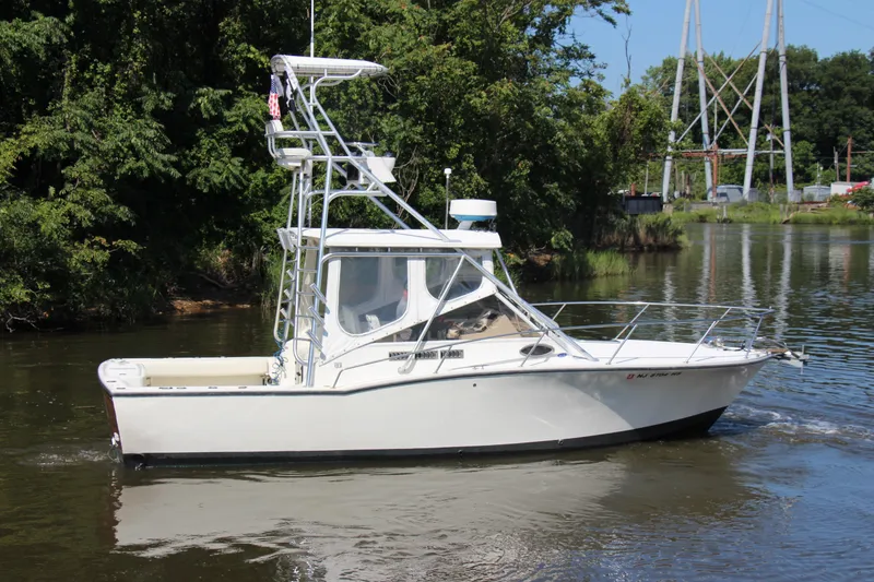 Slide: The Image of 2004 Carolina Classic 28 boat cruising on a calm river with lush greenery. - 52