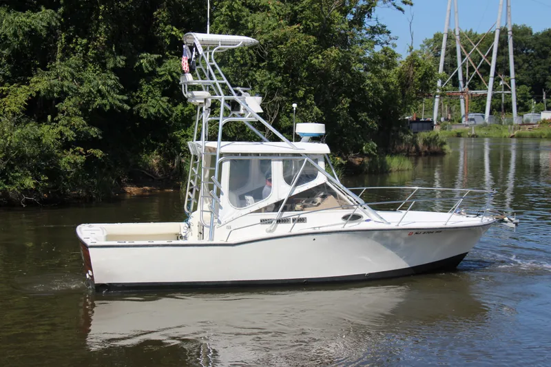Slide: The Image of 2004 Carolina Classic 28 boat cruising on a calm river with lush greenery. - 53