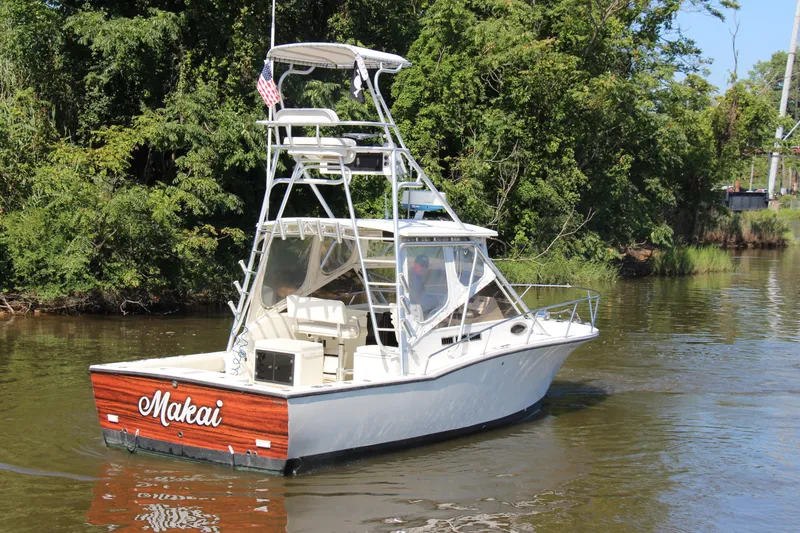Slide: The Image of 2004 Carolina Classic 28 boat named "Makai" cruising on a river with lush greenery. - 57