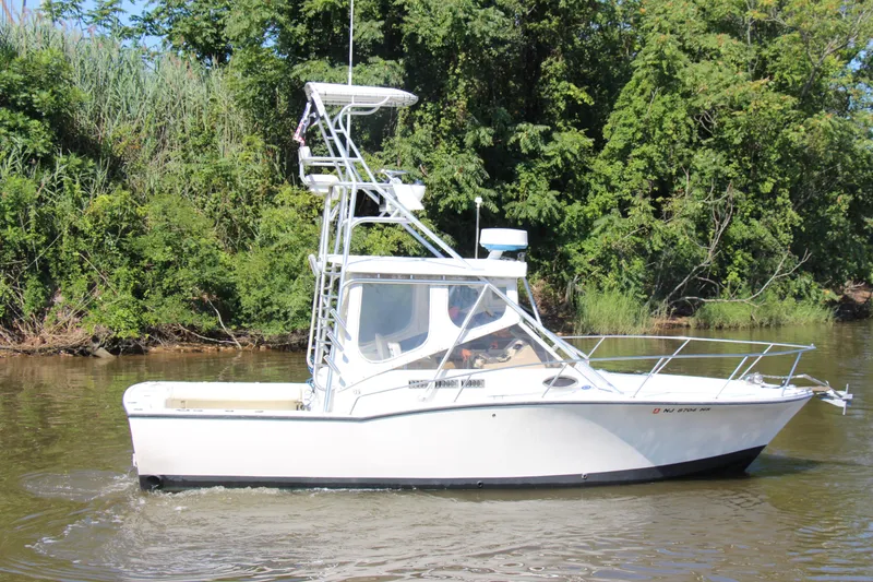 Slide: The Image of 2004 Carolina Classic 28 boat cruising on a river with lush green trees. - 60