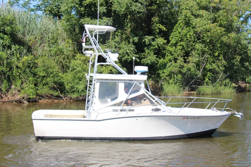 Slide: The Image of 2004 Carolina Classic 28 boat cruising on a calm river with lush green trees. - 61