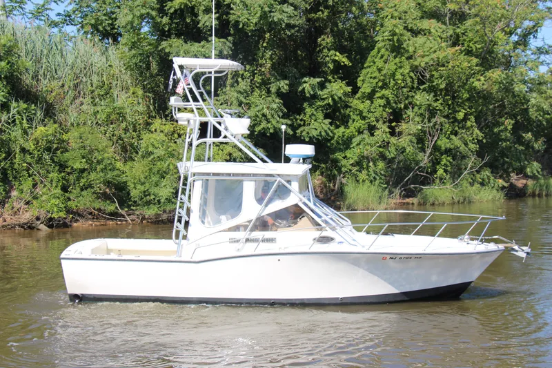 Slide: The Image of 2004 Carolina Classic 28 boat cruising on a river with lush green trees in the background. - 62