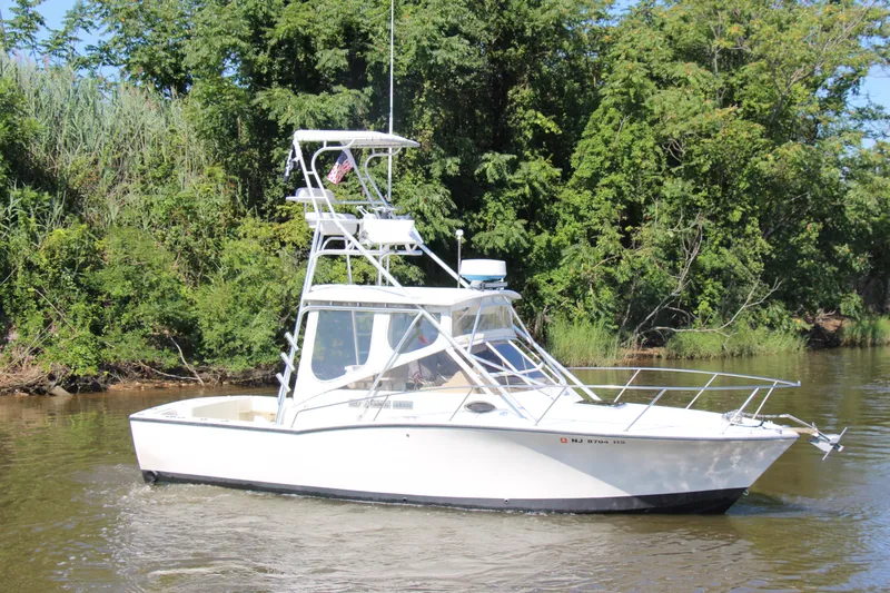 Slide: The Image of 2004 Carolina Classic 28 boat cruising on a river with lush green trees. - 63