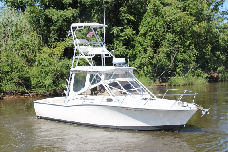 Slide: The Image of 2004 Carolina Classic 28 boat cruising on a river with lush green trees. - 64