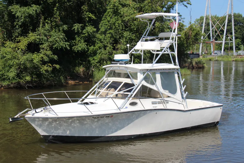 Slide: The Image of 2004 Carolina Classic 28 boat on a calm river, surrounded by lush greenery. - 69