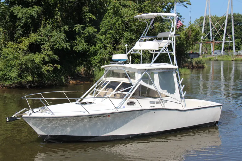 Slide: The Image of 2004 Carolina Classic 28 boat on a calm river, surrounded by lush greenery. - 70