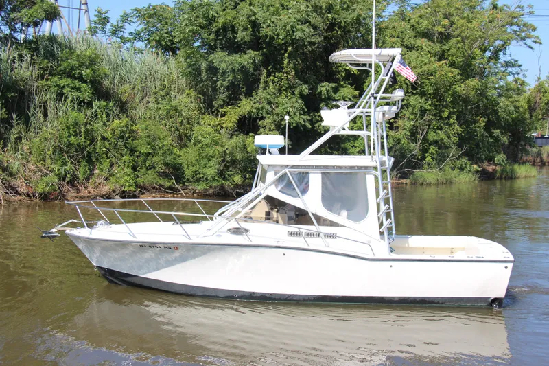 Slide: The Image of 2004 Carolina Classic 28 boat on a calm river, surrounded by lush greenery. - 71
