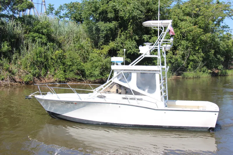 Slide: The Image of 2004 Carolina Classic 28 boat on a calm river, surrounded by lush greenery. - 72