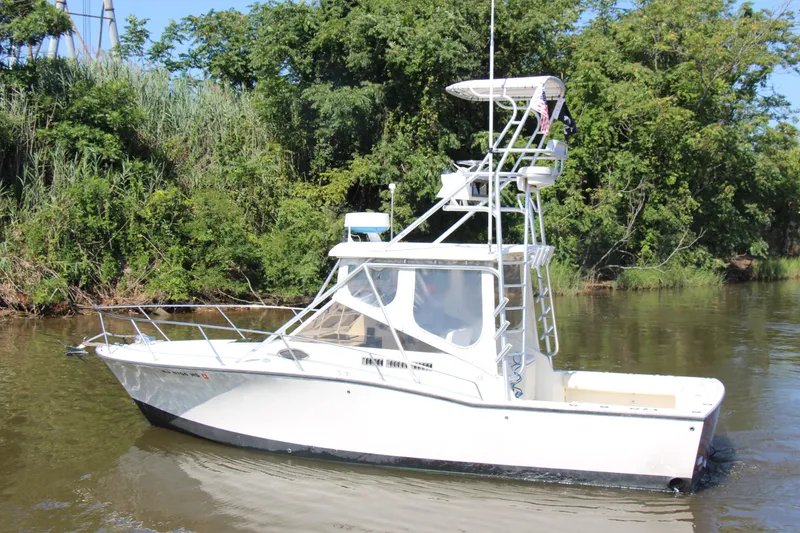 Slide: The Image of 2004 Carolina Classic 28 boat cruising on a calm river with lush green trees. - 73