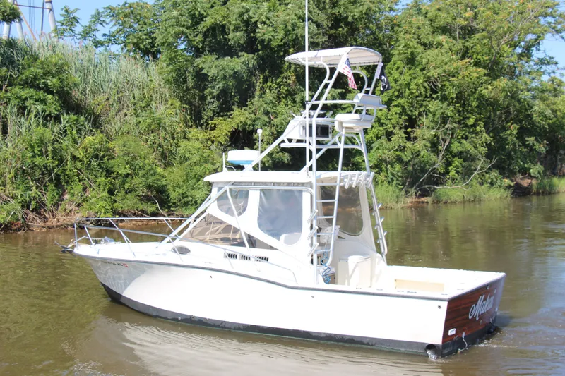 Slide: The Image of 2004 Carolina Classic 28 boat cruising on a river with lush green trees. - 74