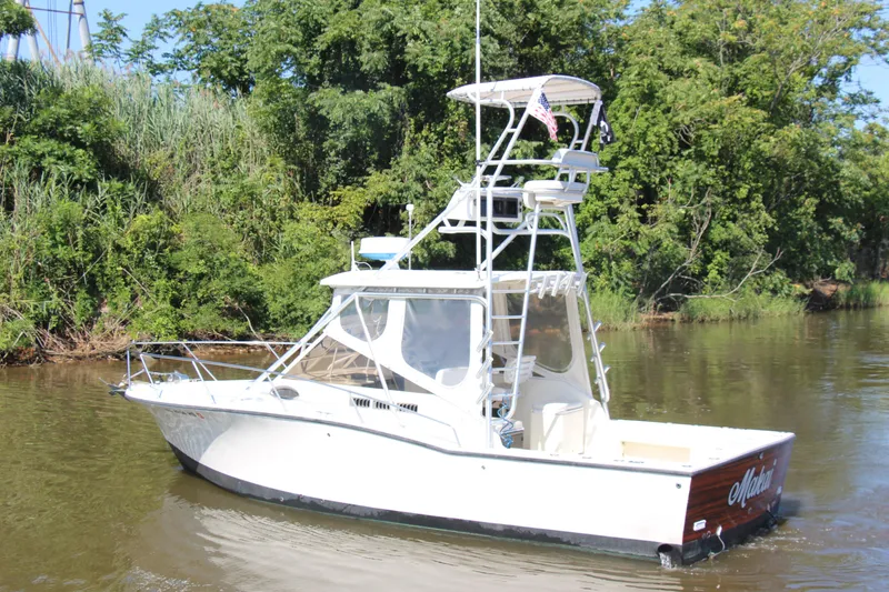 Slide: The Image of 2004 Carolina Classic 28 boat on a calm river with lush green trees. - 75