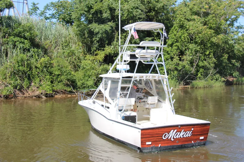 Slide: The Image of 2004 Carolina Classic 28 boat named "Makai" cruising on a river with lush greenery. - 78
