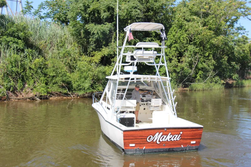 Slide: The Image of 2004 Carolina Classic 28 boat named "Makai" on a river, surrounded by lush greenery. - 79