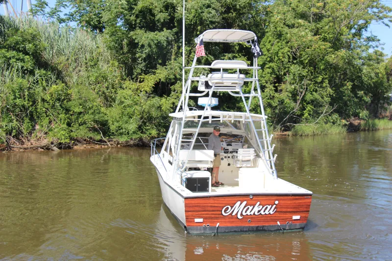 Slide: The Image of 2004 Carolina Classic 28 boat named "Makai" on a river, surrounded by lush greenery. - 80