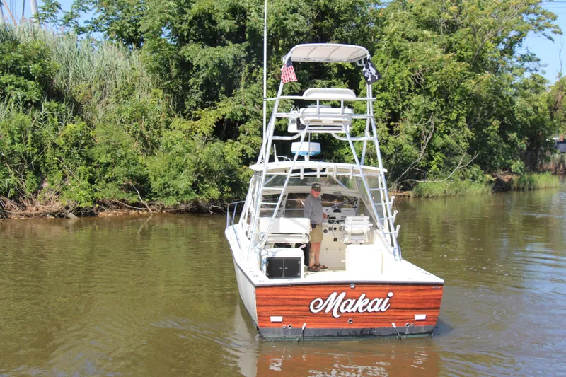 Slide: The Image of 2004 Carolina Classic 28 boat named "Makai" on a calm river, surrounded by lush greenery. - 81