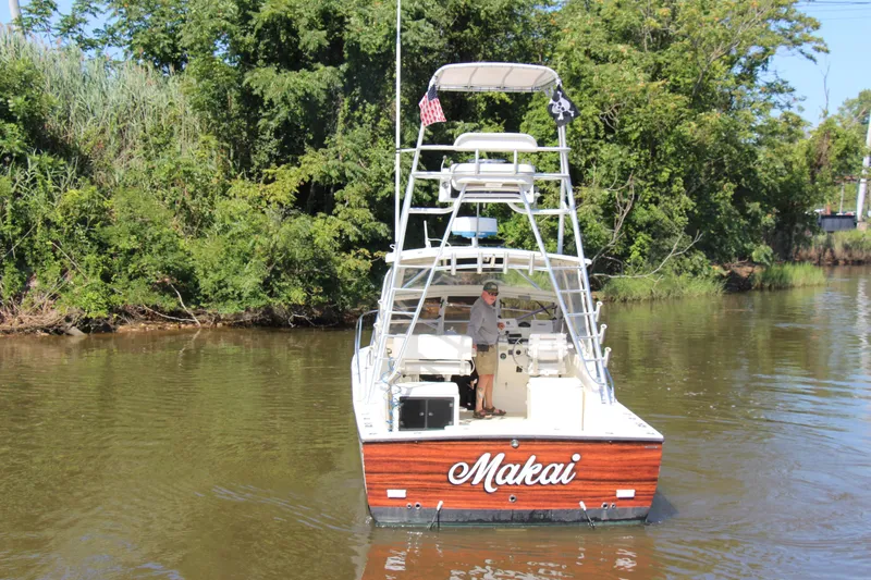 Slide: The Image of 2004 Carolina Classic 28 boat named "Makai" on a calm river, surrounded by lush greenery. - 82