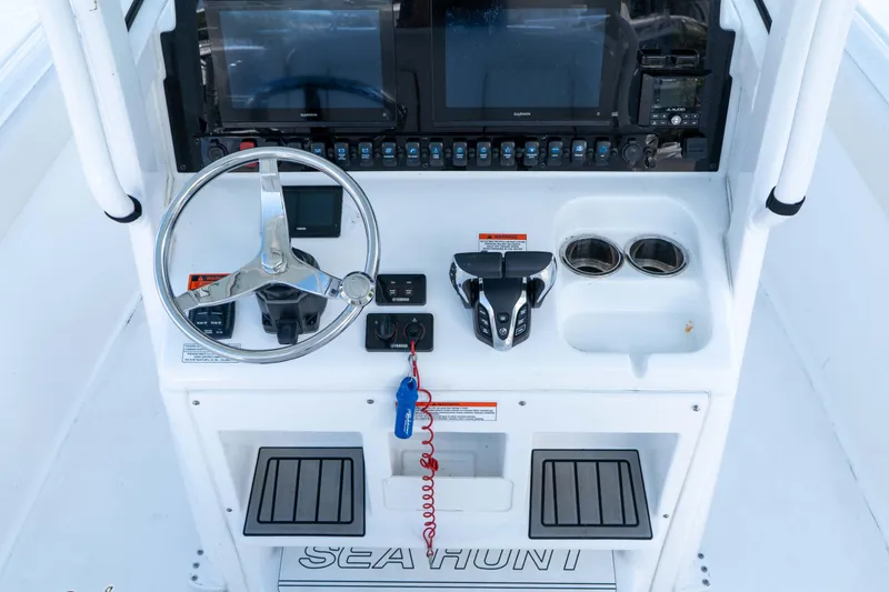 Slide: The Image of 2022 Sea Hunt Gamefish 27 Coffin Box helm with steering wheel, controls, and cup holders. - 16
