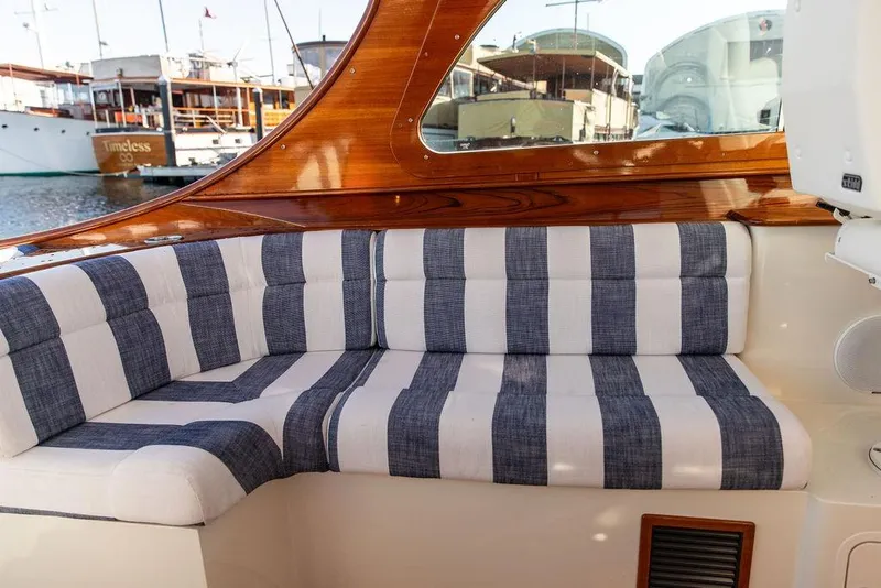 Slide: The Image of 2023 Hinckley Picnic Boat 34 S interior with striped seating and wooden accents. - 12
