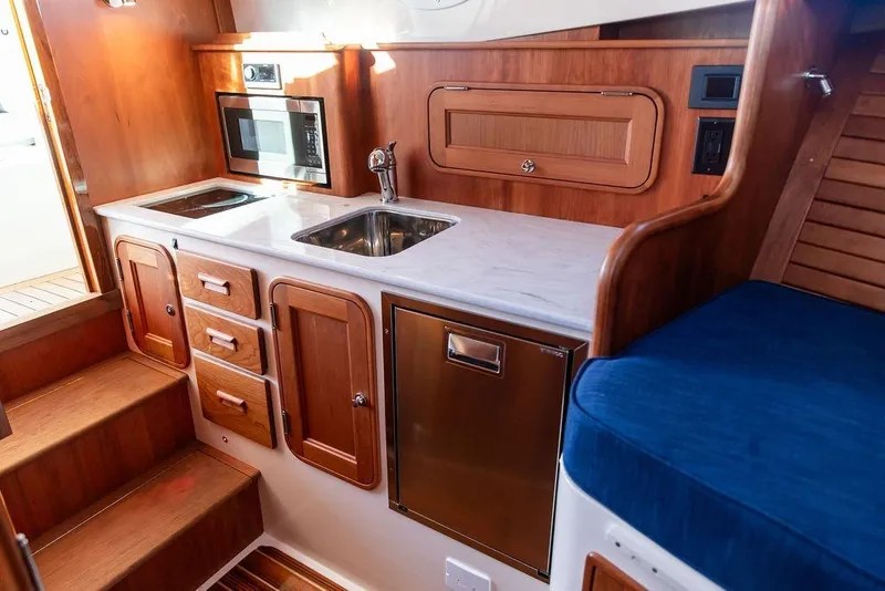 Slide: The Image of 2023 Hinckley Picnic Boat 34 S galley with wood cabinetry and modern appliances. - 19